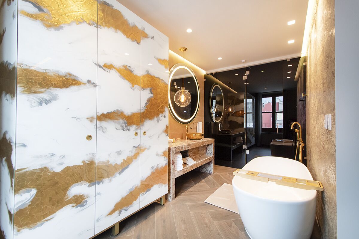A modern bathroom with a marble vanity, a freestanding bathtub, and a large mirror.