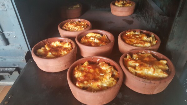 Six terracotta dishes with baked food, placed on a dark surface. - Sullu Dag Evi (Dereli)