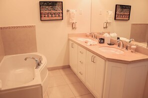 A bathroom with a bathtub, two sinks, and a large mirror. - Palm Beach Condo 202  - A Vacation Rental by Bougainvillea Barbados (Hastings)
