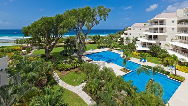 A resort with a pool, palm trees, and a view of the ocean. - Palm Beach Condo 202  - A Vacation Rental by Bougainvillea Barbados (Hastings)