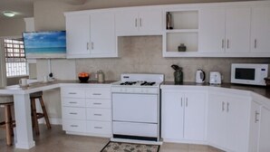 Una cocina con armarios blancos, estufa, microondas y cafetera.