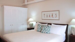 Un dormitorio con una cama grande, dos mesitas de noche, un armario blanco y un cuadro enmarcado en la pared.