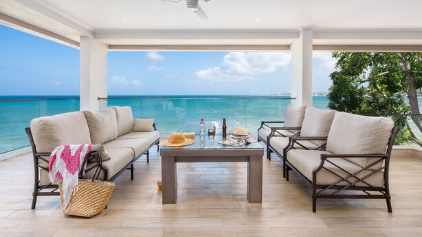 A balcony with two sofas, a table, and a ceiling fan.