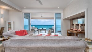 A spacious living area with a view of the ocean, a dining table, and a seating area with a sofa and chairs.