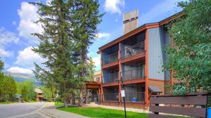 A multi-story building with balconies, a paved road, and a bench. - 3bd_atrium_302 (Breckenridge)