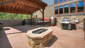 An outdoor patio with a stone fire pit, a grill, and a covered seating area. - 3bd_atrium_302 (Breckenridge)
