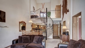 A spacious living room with a large sectional sofa, a coffee table, and a staircase leading to an upper level. - 3bd_atrium_302 (Breckenridge)