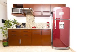 A compact kitchen with a microwave, coffee maker, and a red refrigerator. - Kingsize 1bdr apt, common rooftop w/ lounge area, pool, BBQ... (units 202) (Playa Del Carmen)