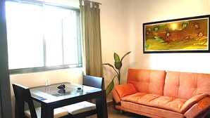 A living room with a dining table, a sofa, a potted plant, and a framed picture on the wall. - Kingsize 1bdr apt, common rooftop w/ lounge area, pool, BBQ... (units 202) (Playa Del Carmen)