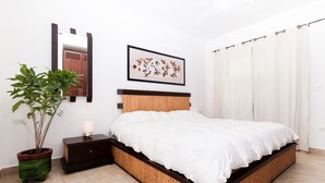 A bedroom with a bed, a bedside table, a potted plant, a mirror, and a framed picture on the wall. - Kingsize 1bdr apt, common rooftop w/ lounge area, pool, BBQ... (units 202) (Playa Del Carmen)