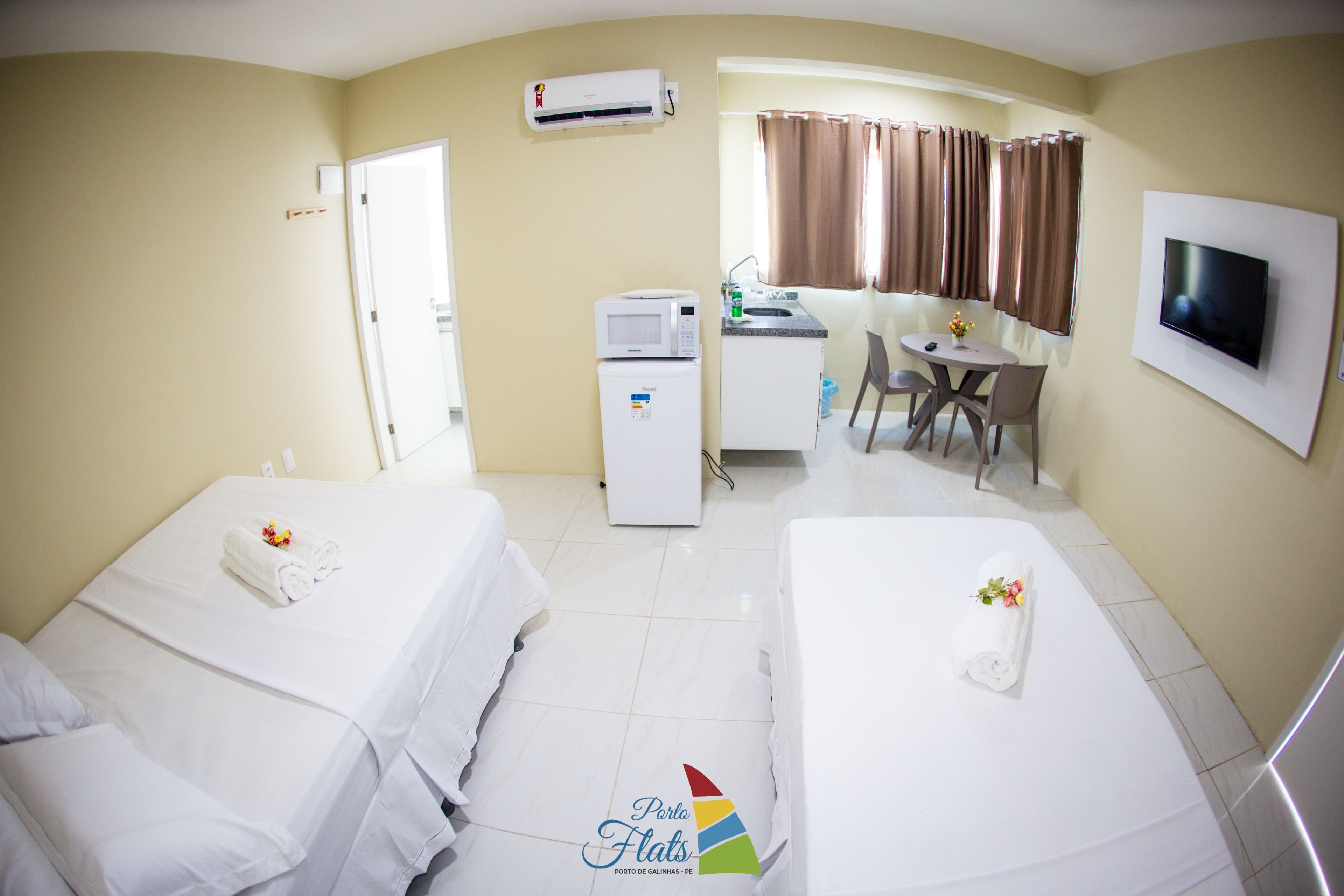 Une chambre d’hôtel avec deux lits, une kitchenette, un coin repas et un téléviseur.
