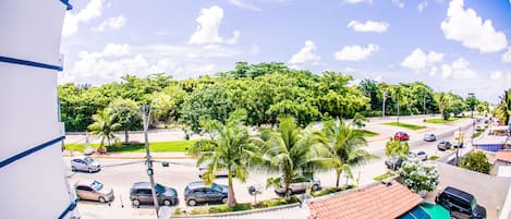 A residential area with a swimming pool, parked cars, and palm trees.