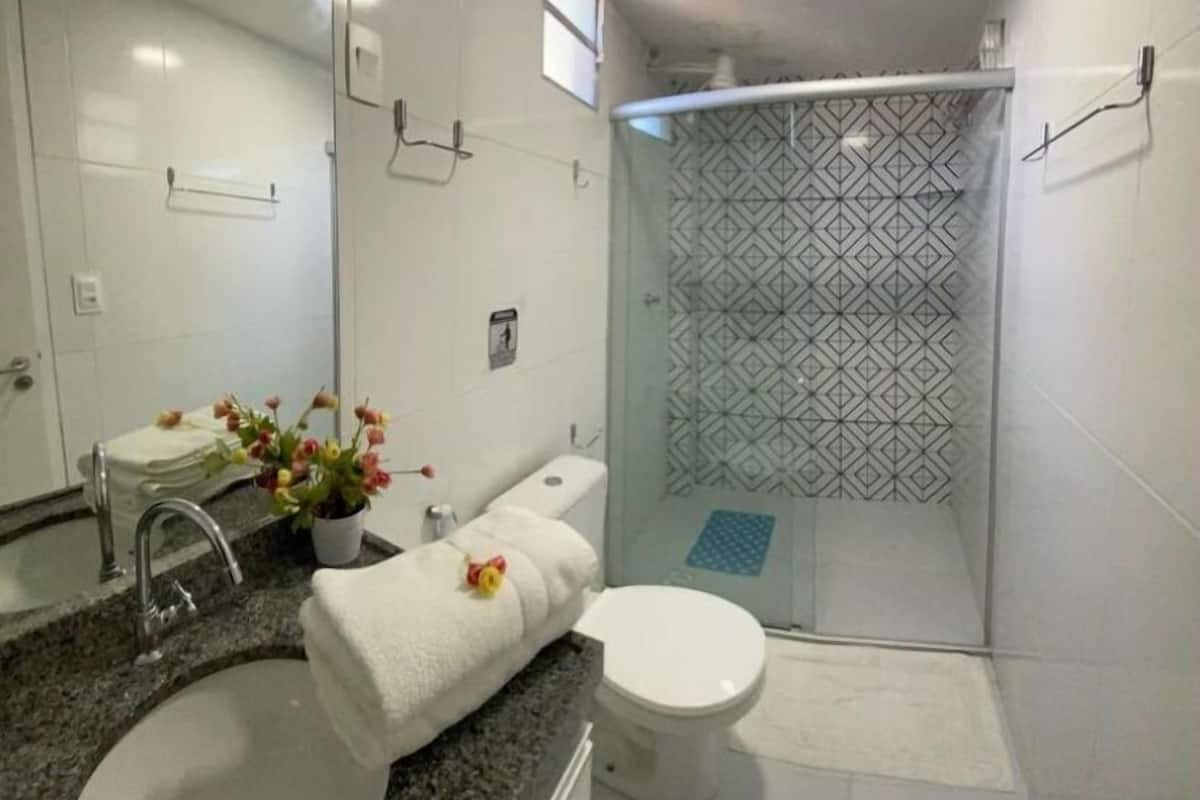 Un baño moderno con lavamanos, inodoro y ducha.