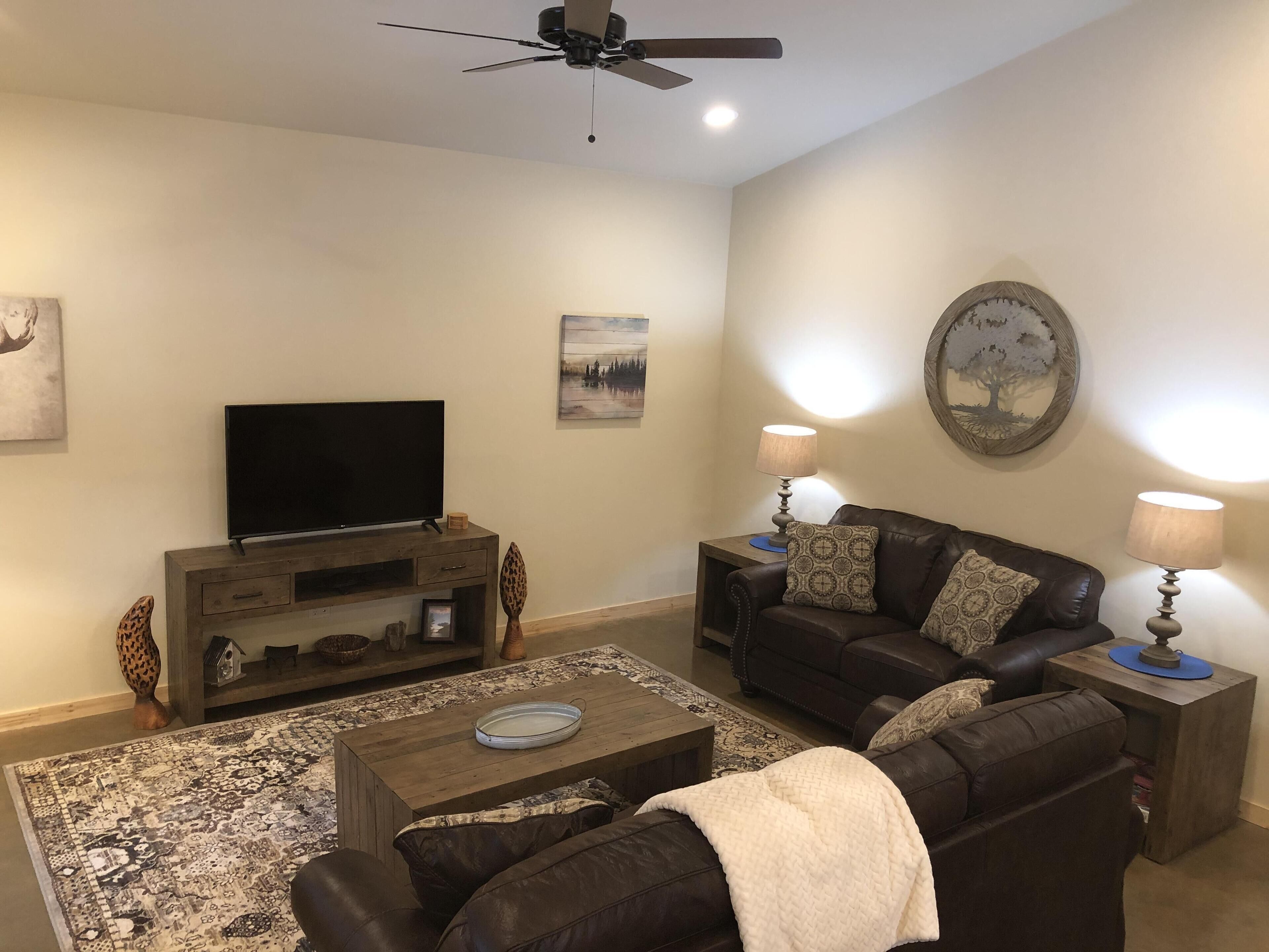 A living room with a flat-screen TV, two sofas, a coffee table, and a patterned rug.
