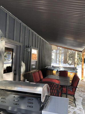 An outdoor seating area with a grill, red chairs, and a view of the snowy landscape.