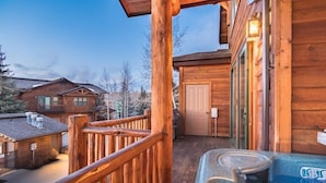 Una cabaña de madera con jacuzzi y terraza.