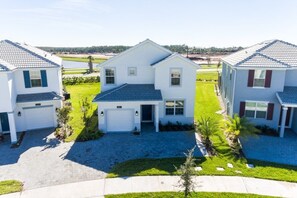 A modern two-story house with a garage, a well-maintained lawn, and a clear view of the surrounding area. - 5BR Pool Home in Storey Lake by SHV-4817 (Kissimmee)