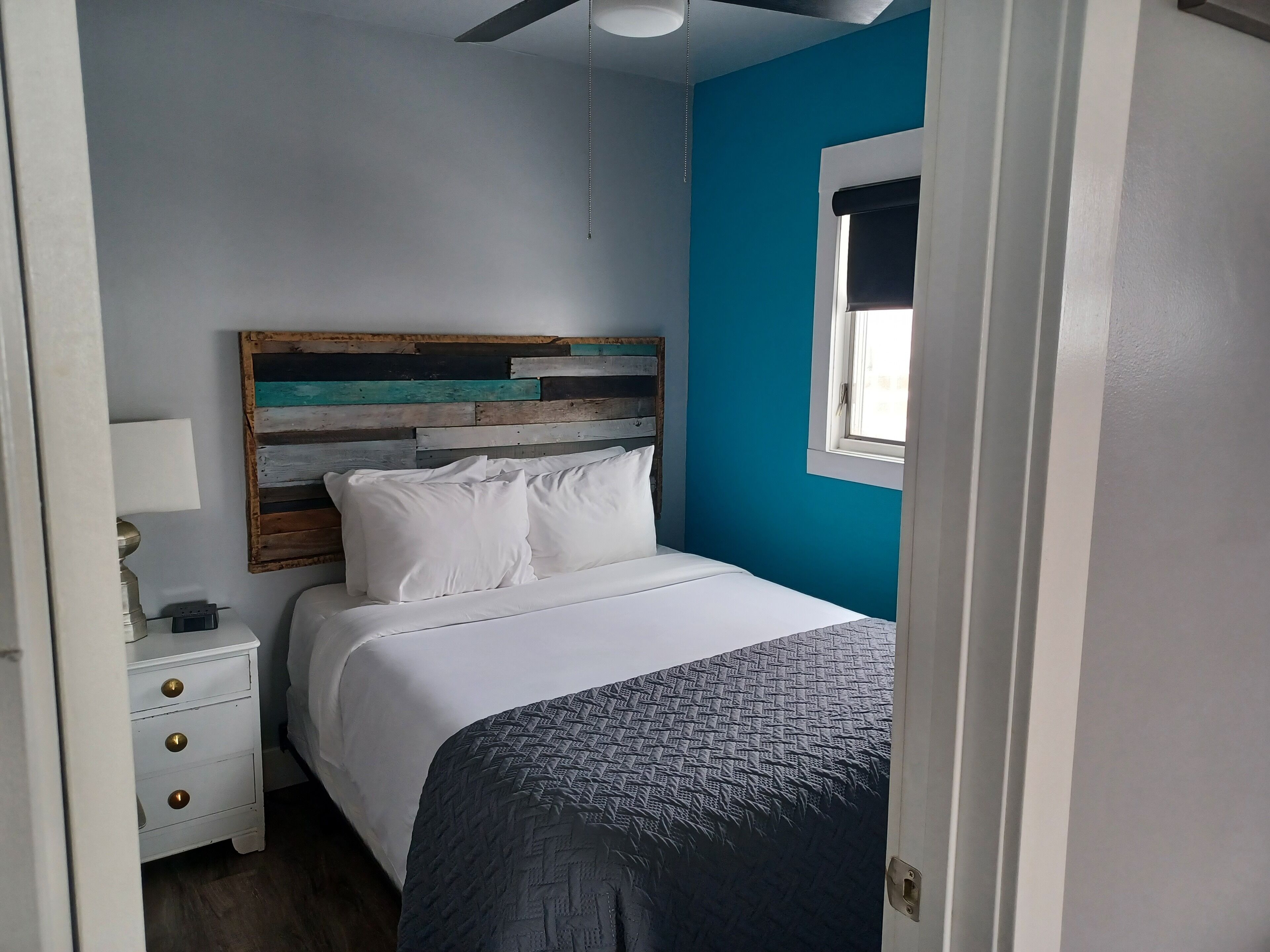 A bedroom with a bed, a nightstand, a lamp, and a window with a view.