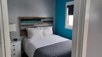 A bedroom with a bed, a nightstand, a lamp, and a window with a view.