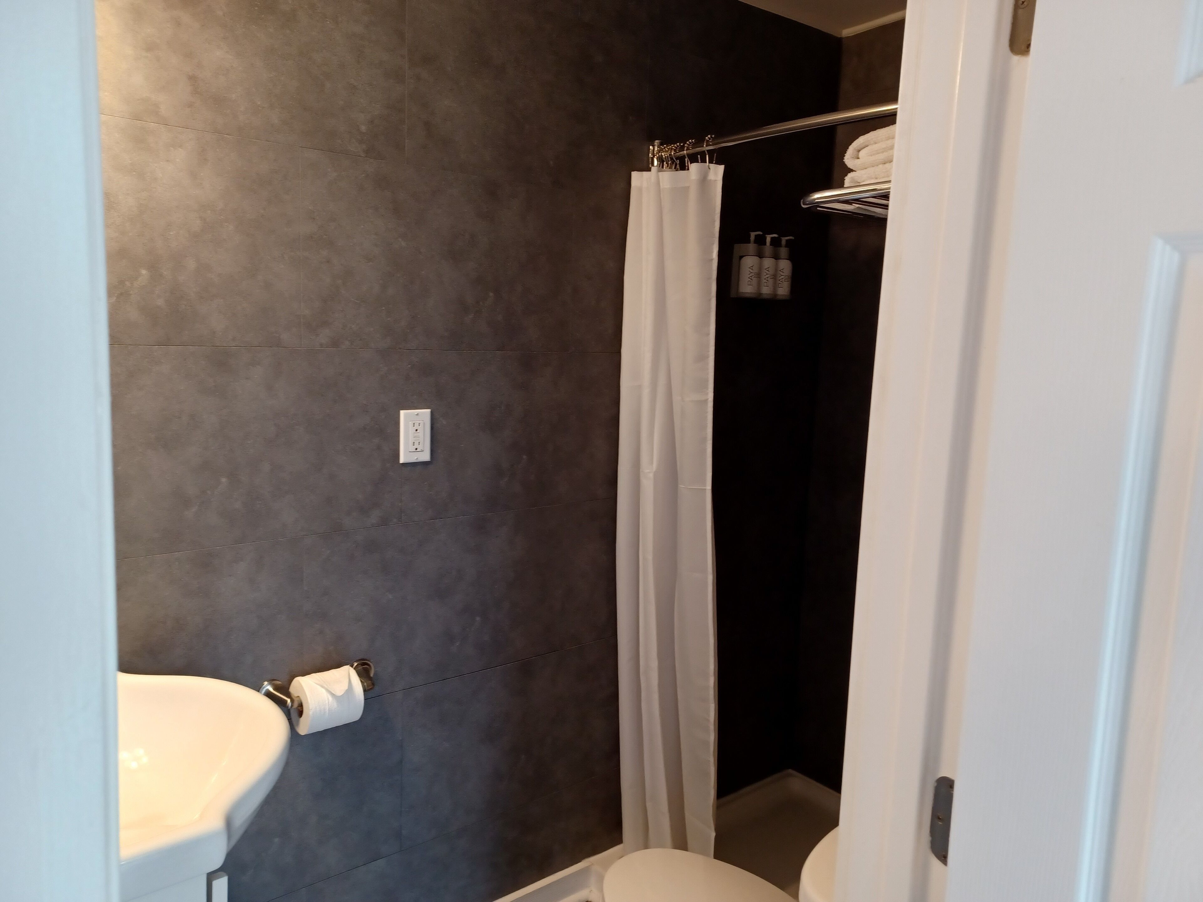 Un baño con inodoro, lavamanos, cortina de ducha y toallero.