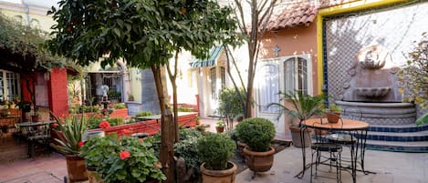 An outdoor patio with potted plants, a fountain, and outdoor seating.