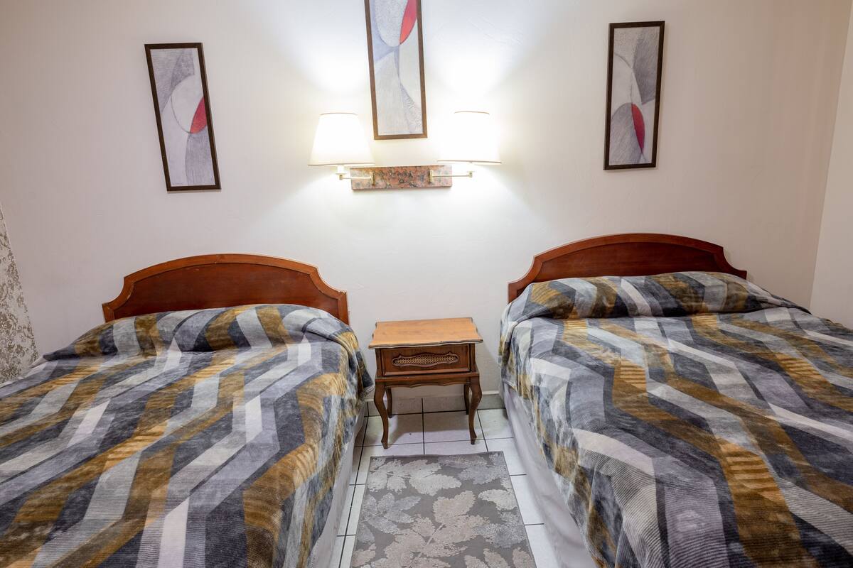 Ein Hotelzimmer mit zwei Betten, einem Nachttisch und Wandlampen.