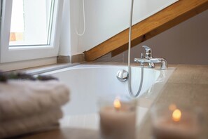 A modern bathroom with a bathtub, a wooden ceiling beam, and a window. - Villa Olive Tree (Omis)