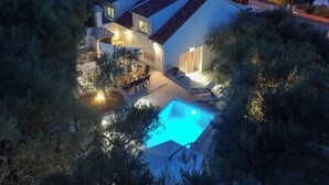 Ein modernes Haus mit Schwimmbad, umgeben von Bäumen und mit Blick auf ein Gewässer.