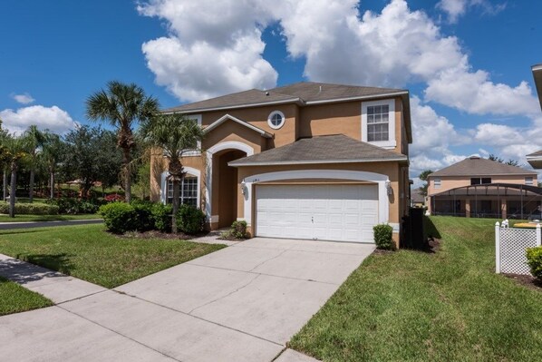 A residential house with a garage, a driveway, and a well-maintained lawn.