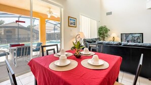 A dining area with a red tablecloth, white plates, and a view of a pool and outdoor seating. - 7BR Pool Home Emerald Island by SHV-2793 (Kissimmee)