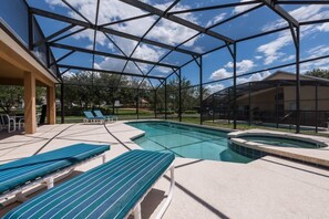 A covered outdoor swimming pool with lounge chairs and a hot tub.