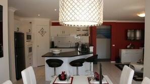 Une cuisine moderne dotée d’un îlot central, de meubles blancs et d’un lustre.