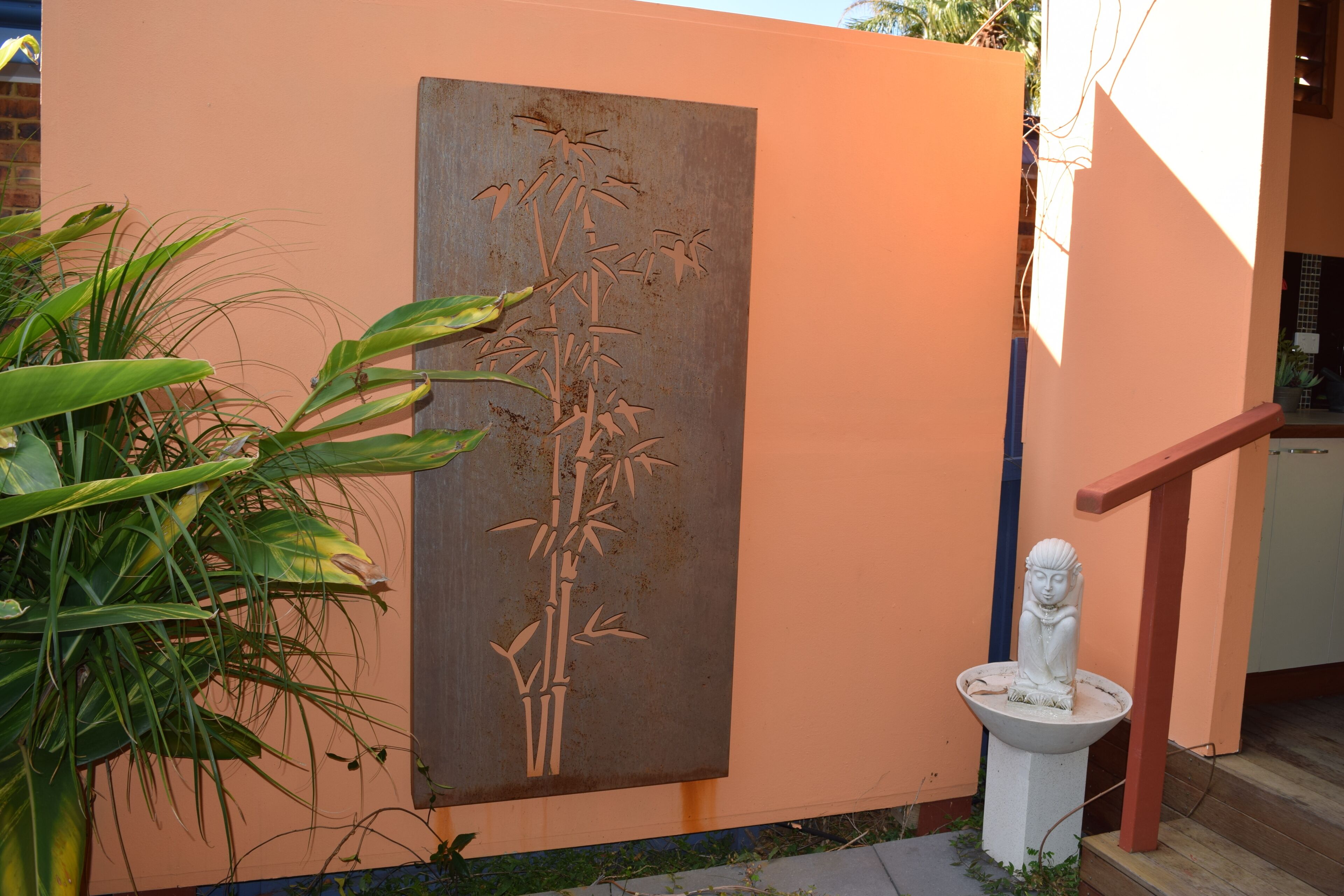 Pared con un relieve de planta de bambú, una estatua blanca y una barandilla roja.