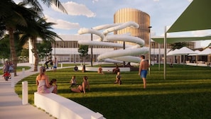 Un edificio moderno con una estructura espiral distintiva al fondo, rodeado de un césped cuidado con gente y palmeras.