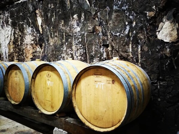 Wooden barrels stacked against a stone wall.