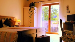 Un dormitorio con cama, mesita de noche, lámpara y vistas al exterior.