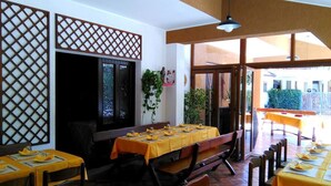 Un restaurante con mesas y bancos de madera, un separador de celosía y vistas al exterior.