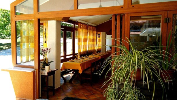 Un restaurante con una larga mesa de comedor, vigas de madera y ventanas amplias.