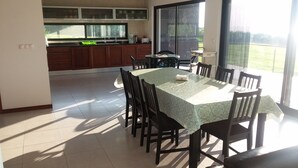 A spacious dining area with a table and chairs, a kitchen in the background, and a large sliding glass door leading to a balcony. - Azores Beach Home for adults/children, 3 bed.2 bath, First Fl., 3534/AL (Horta, Azores)