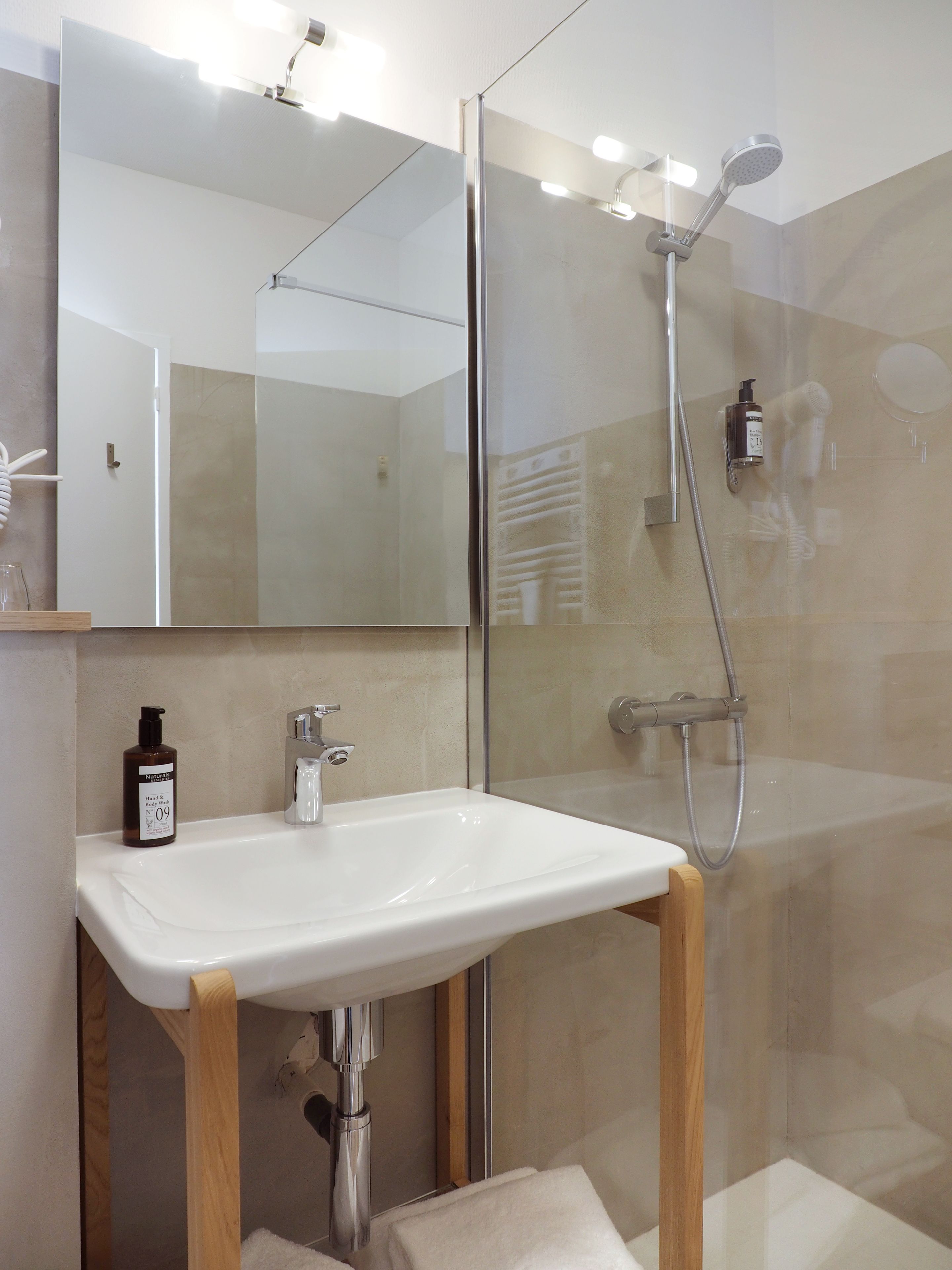 Une salle de bain moderne avec une douche à parois de verre, un lavabo blanc et un miroir au-dessus du lavabo.