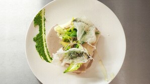 A white plate with a dish of food, possibly sushi, on a metallic surface.