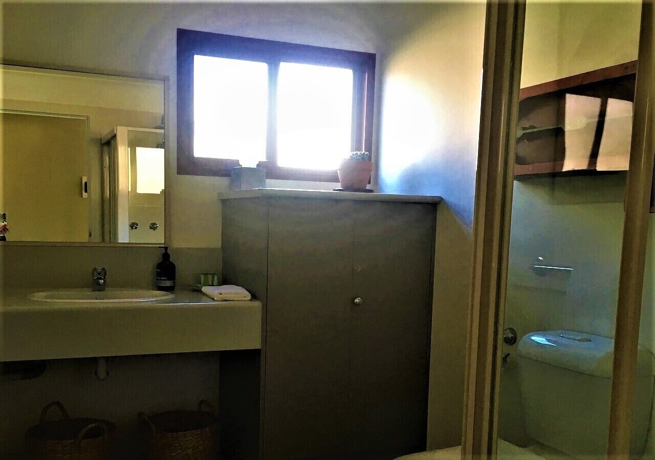 A compact bathroom with a sink, mirror, and window.