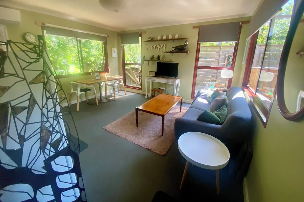 A living room with a sofa, coffee table, TV, and a staircase with a geometric design.