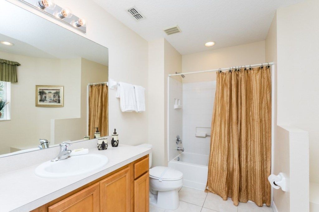 A bathroom with a white sink, a toilet, a shower, and a large mirror.