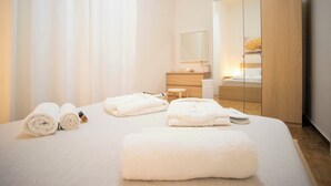 Una camera d'albergo con un letto rifatto, un armadio in legno, un comodino e uno specchio.