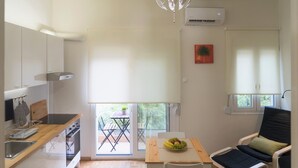 Una cucina compatta con zona pranzo, un tavolo da pranzo con una ciotola di frutta, una sedia e una finestra vista sul verde.
