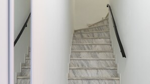Una scala con gradini in marmo e ringhiera nera, che conduce a un piano superiore.