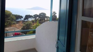 A balcony with a wooden ceiling, a blue door, and a view of the sea and mountains. - Mary Popi (Kalymnos)