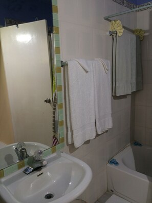 Un baño con lavamanos, espejo, toallero y bañera.