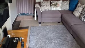 Un salon comprenant un canapé, une table basse, un téléviseur et un miroir fixé au mur.